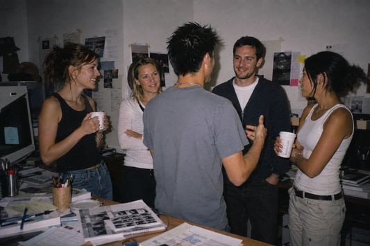 Creative marketing team discussing ideas in an office with notes, sketches, and printed research on the walls.